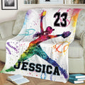 Vibrant softball blanket displayed on a sofa with dynamic female player artwork and colorful softball illustrations