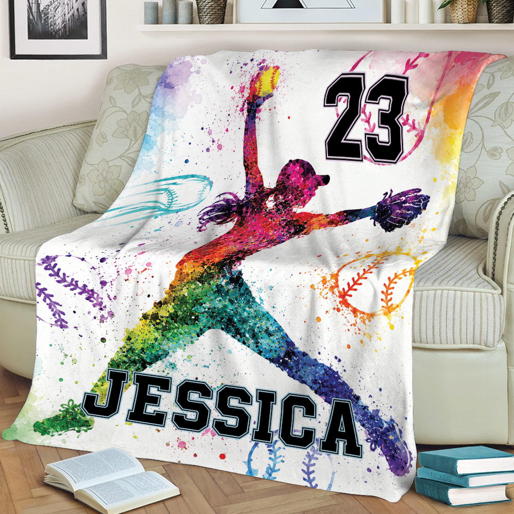 Vibrant softball blanket displayed on a sofa with dynamic female player artwork and colorful softball illustrations