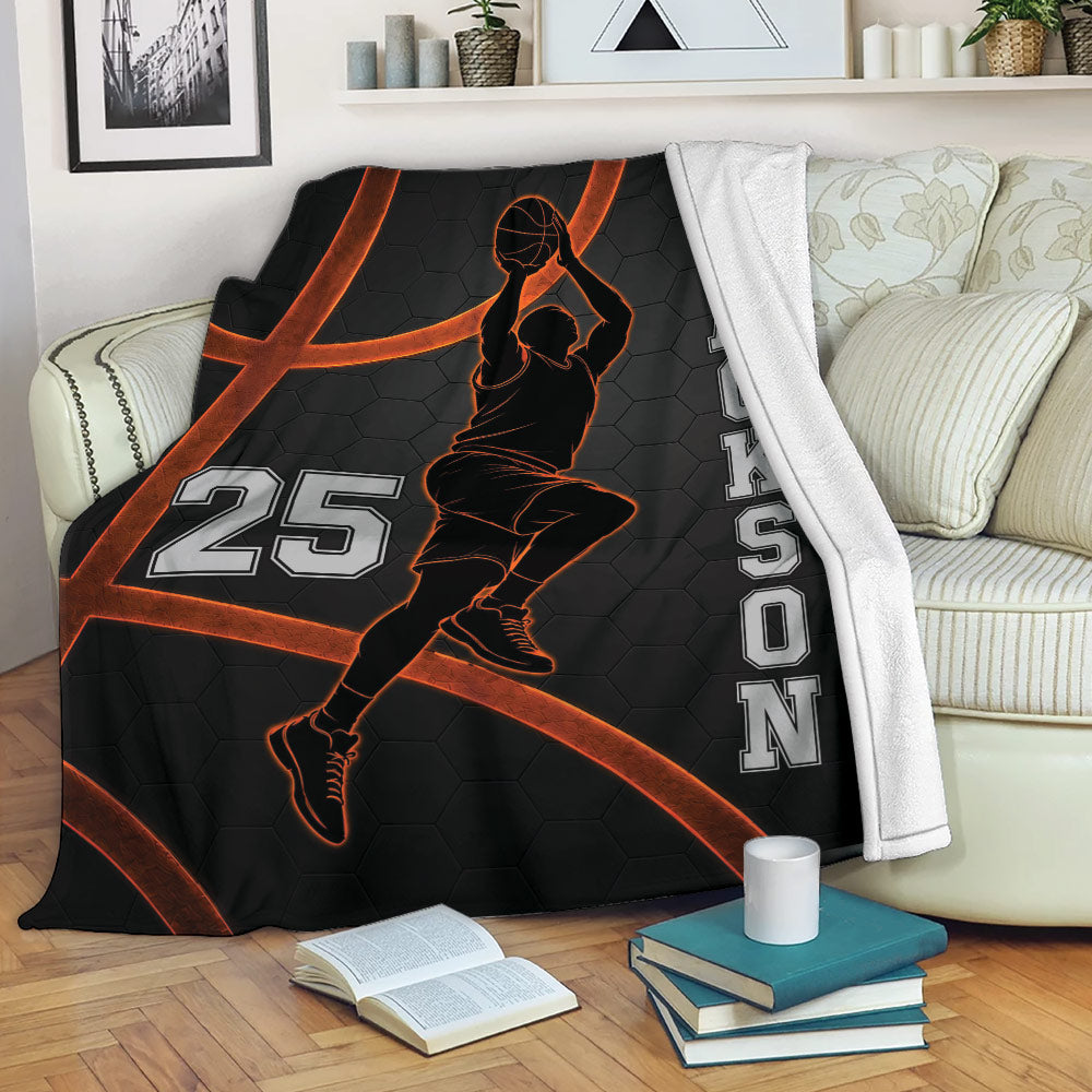 Basketball blanket displayed on a couch with a jumping player silhouette and bold black and orange design