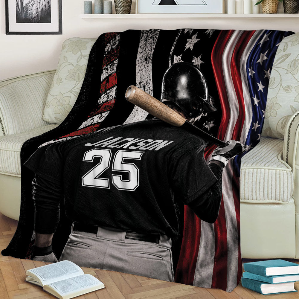 Patriotic baseball throw blanket draped over a couch with batter artwork and bold flag stripes