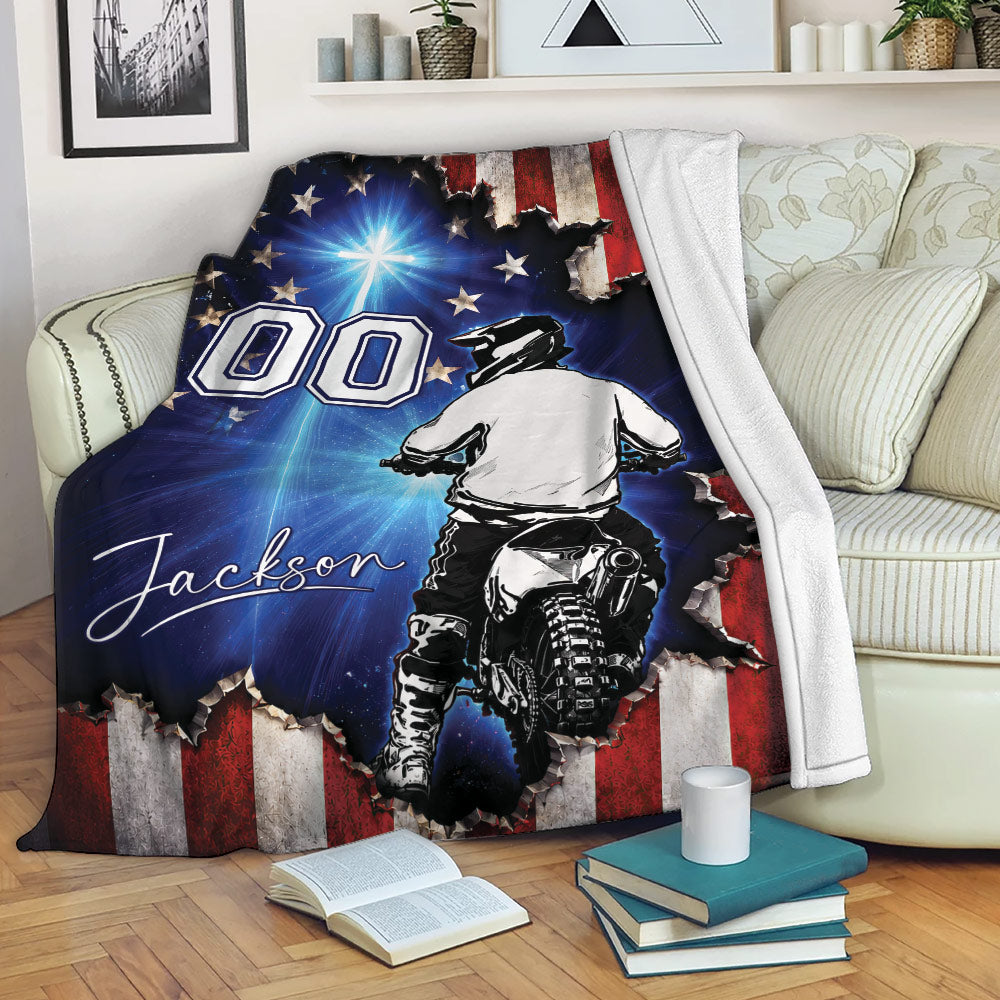Motocross blanket displayed on a couch with dirt bike rider artwork and distressed patriotic flag design