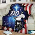 Close view of motocross throw blanket on a sofa featuring a dirt bike rider and bold patriotic artwork