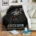 Motocross blanket draped over a couch with dirt bike rider artwork and decorative black and orange border