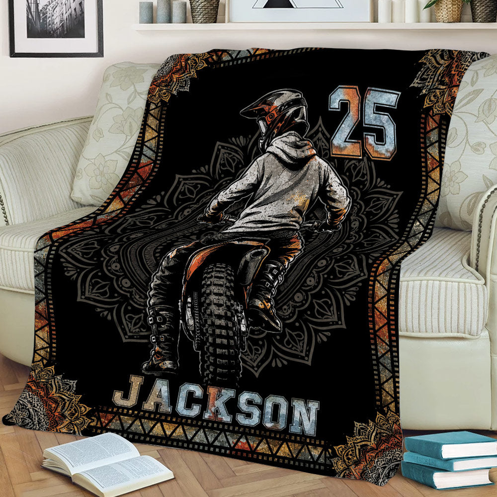 Motocross throw blanket styled on a sofa with dynamic dirt bike rider illustration and bold graphic design