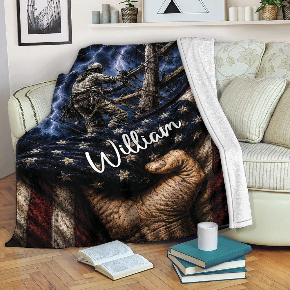 Lineman throw blanket displayed on a sofa with utility worker artwork, lightning, and flag-inspired colors