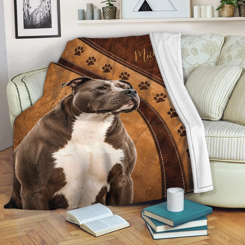 Pitbull blanket draped over a sofa with brown leather-look artwork and paw prints