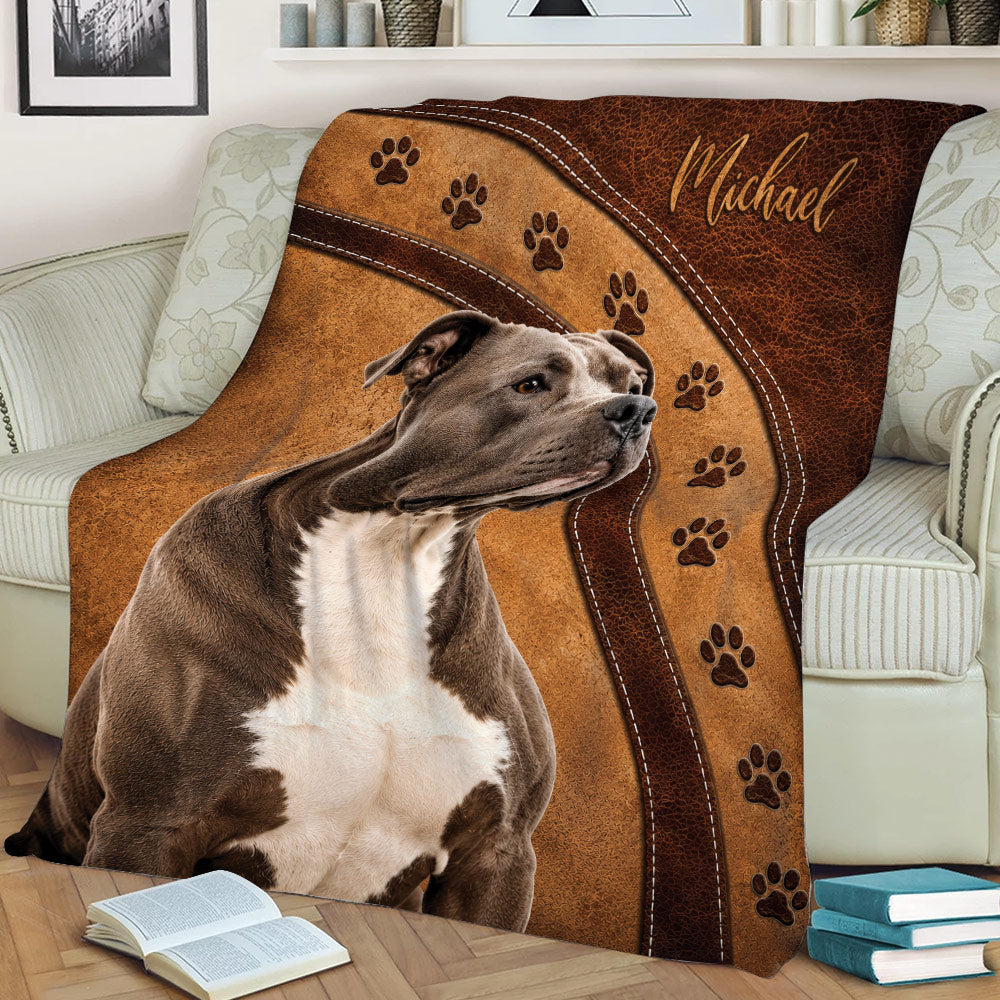 Pitbull throw blanket styled across a sofa with warm brown artwork and repeating paw prints