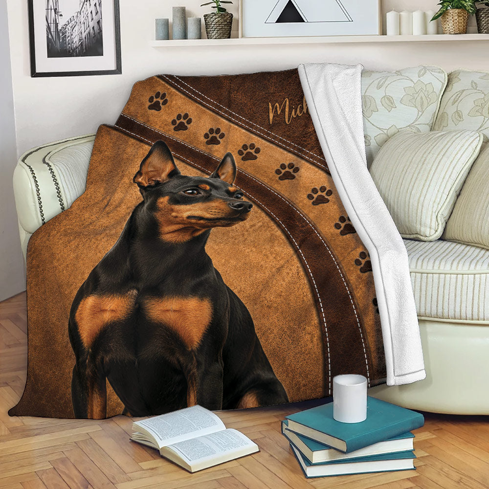 Miniature Pinscher throw blanket displayed on a sofa with paw print details and warm brown artwork