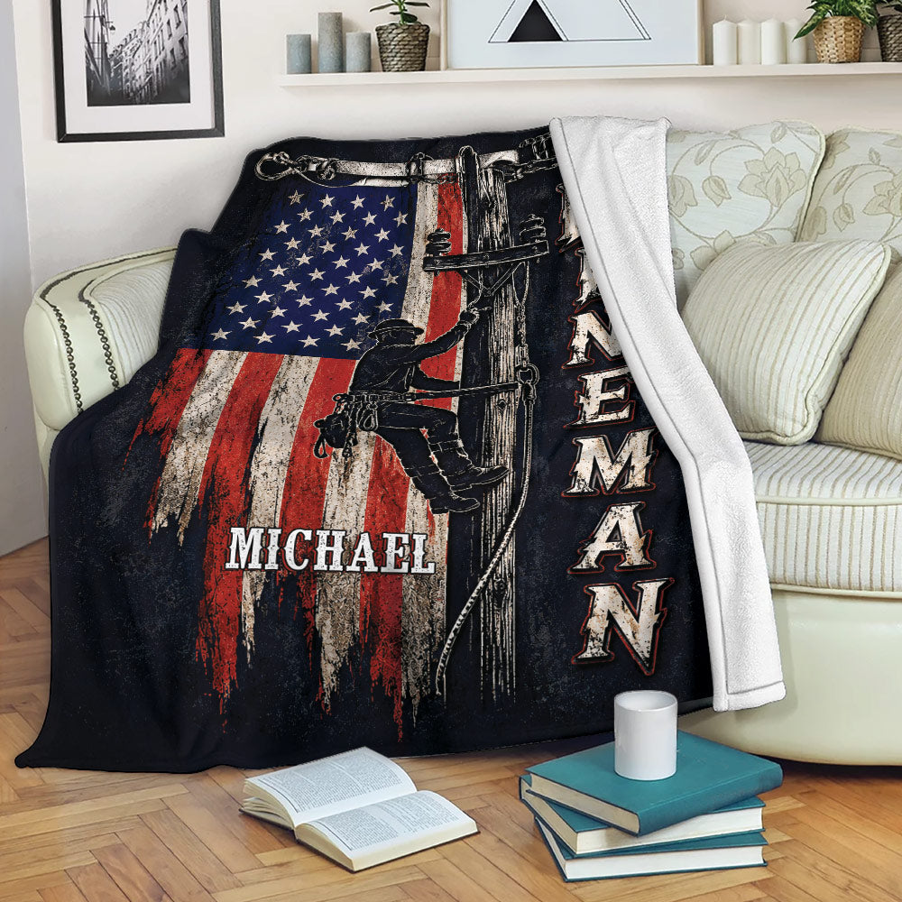 Lineman throw blanket displayed on a sofa with utility worker artwork and patriotic red, white, and blue design