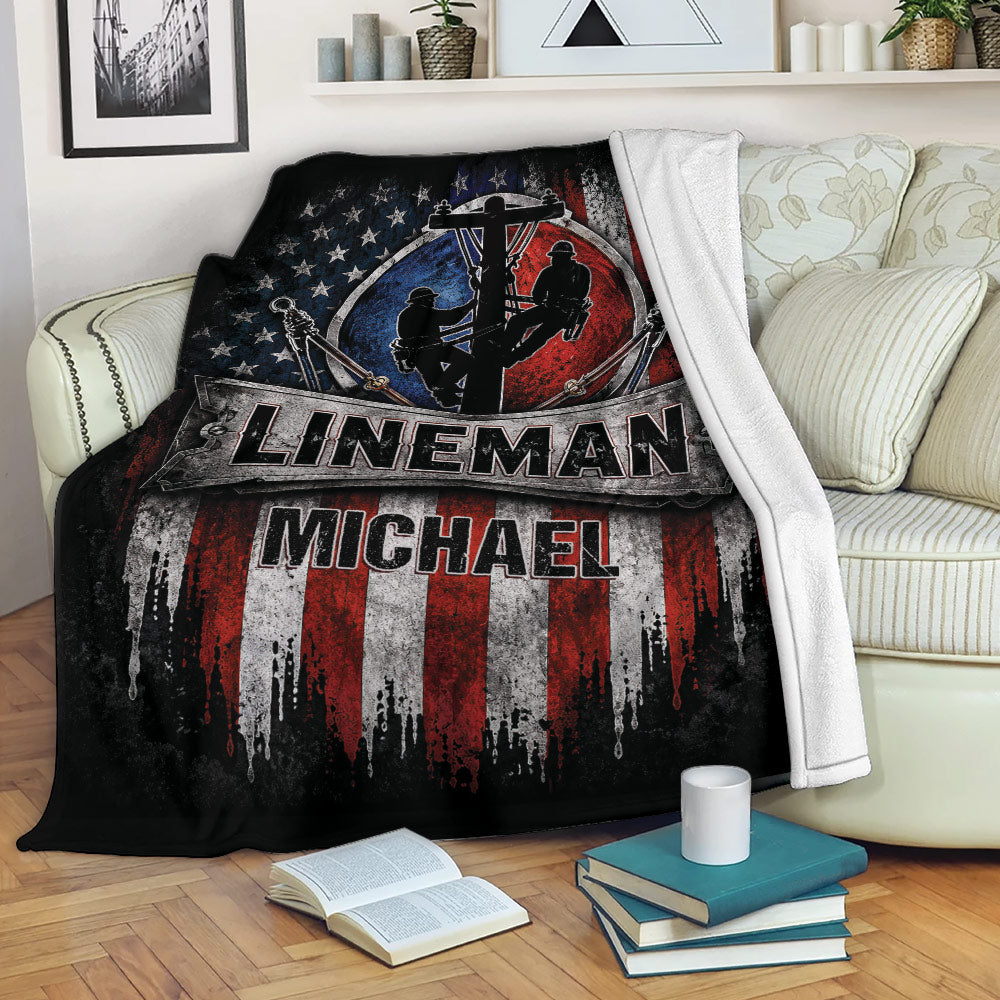 Patriotic lineman blanket displayed on a sofa with utility worker silhouettes and bold red, white, and blue artwork