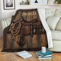 Western cowboy throw blanket draped across a sofa with saddle, rope, leather tack, and rustic wood artwork