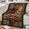 Rustic cowboy blanket draped over a chair with western saddle, hat, lasso, and flag artwork