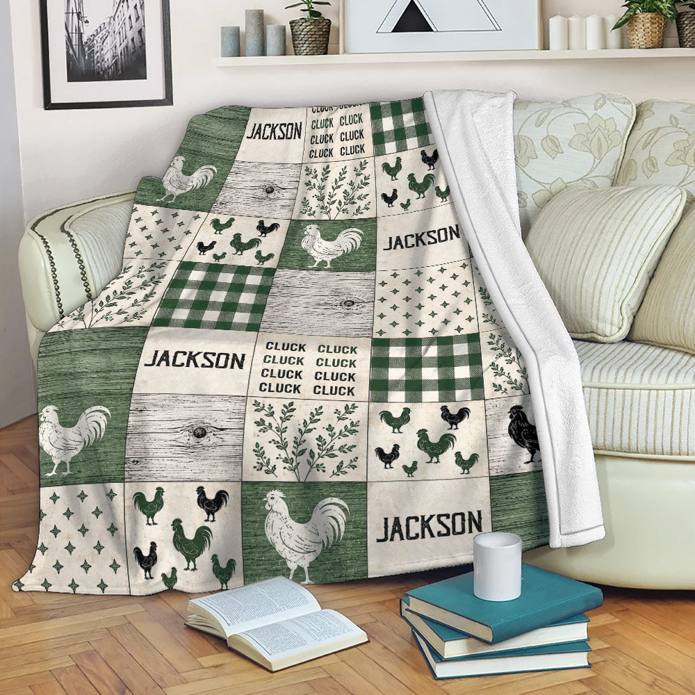 Chicken throw blanket draped over a sofa, featuring rustic rooster artwork, green plaid, and farmhouse patchwork styling