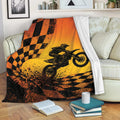 Motocross blanket draped over a sofa with a dirt bike rider, orange racing colors, and dramatic checkered flag design