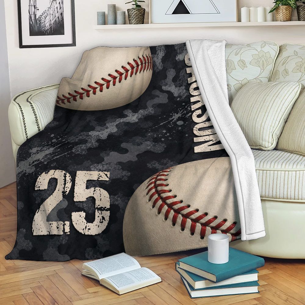 Baseball blanket displayed across a sofa with dark camouflage graphics and oversized baseball artwork