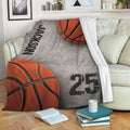 Basketball blanket displayed on a sofa with bold orange basketball graphics and gray background