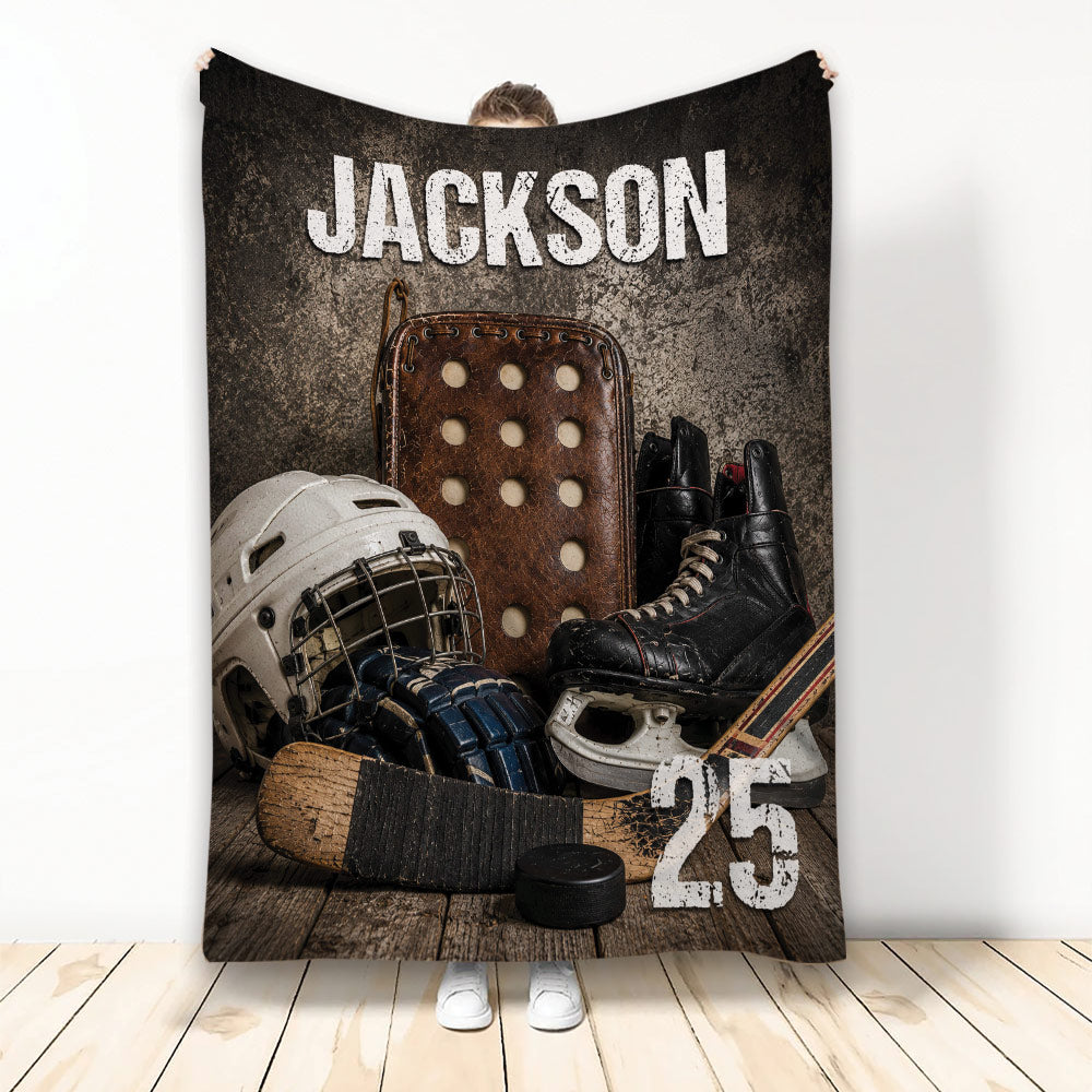 Hockey throw blanket displayed upright with vintage gear artwork, helmet, skates, stick and puck