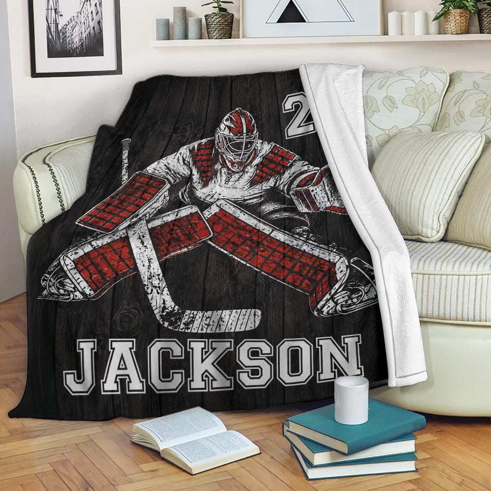 Hockey goalie throw blanket draped over a couch with bold red, black and white sports artwork