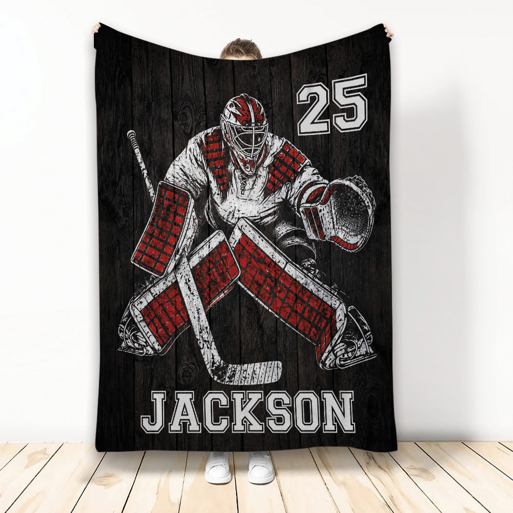 Hockey throw blanket displayed upright with red and black goalie artwork on a dark woodgrain background