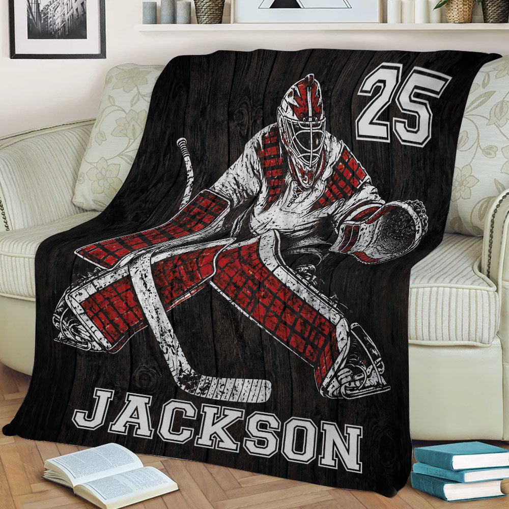 Close view of a hockey goalie throw blanket displayed on a sofa with dramatic red and black artwork