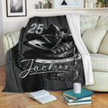 Hockey throw blanket draped over a sofa with black and white skates, hockey stick, puck, and sports artwork