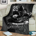Black and white ice hockey blanket displayed on a couch with skates, stick, puck, and bold sports design