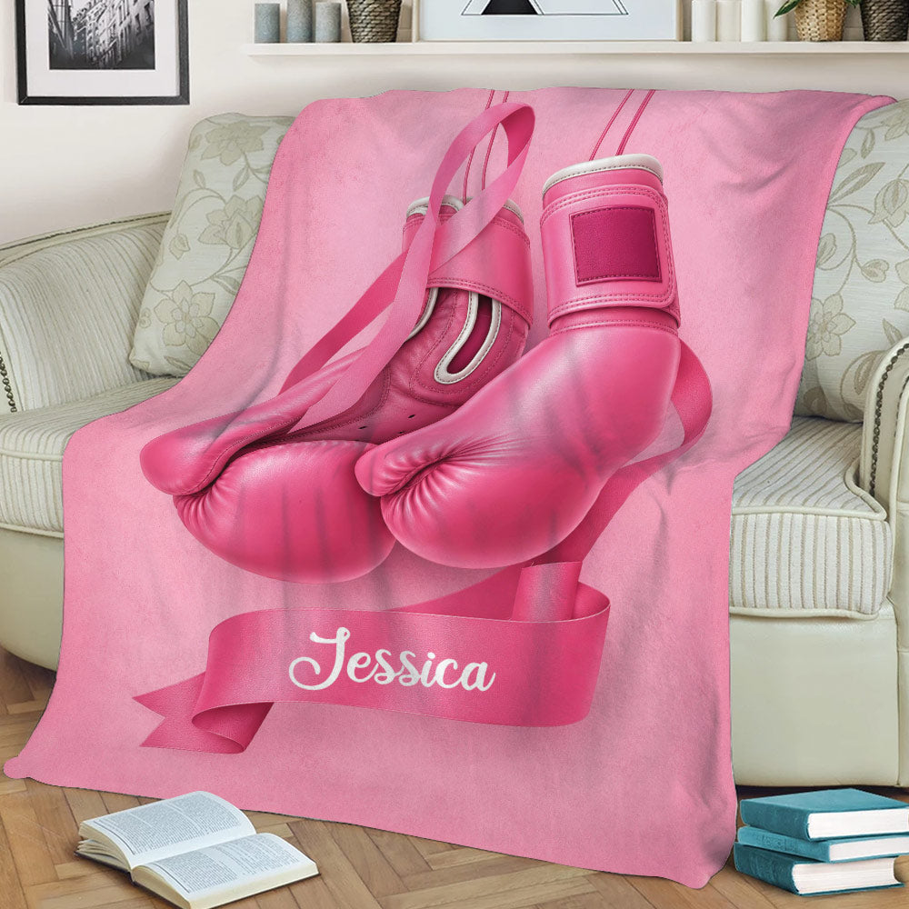 Breast cancer awareness throw blanket with pink boxing gloves and ribbon artwork on a couch