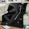 Turntable DJ throw blanket draped across a sofa, featuring black vinyl record and mixer artwork