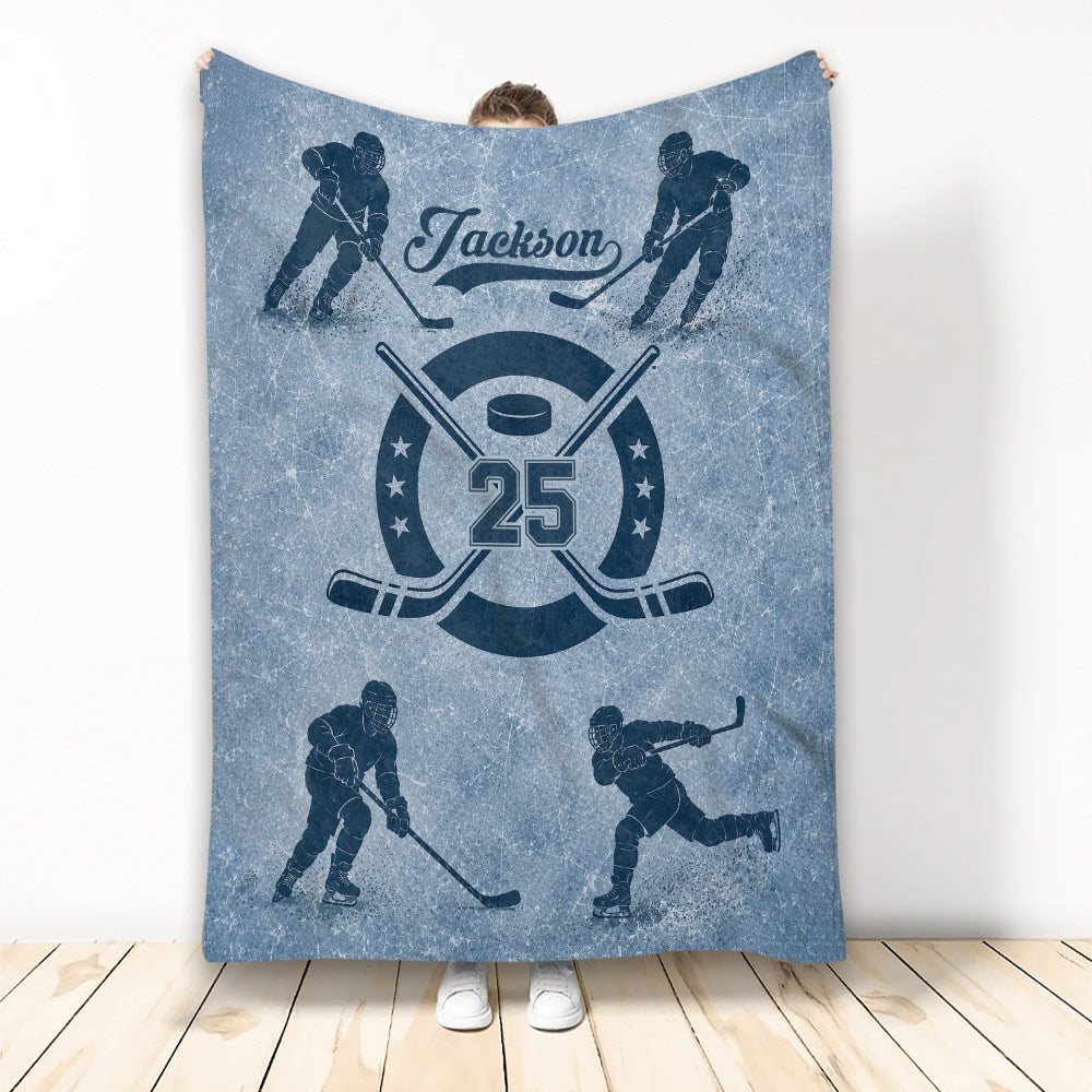 Blue hockey throw blanket featuring illustrated players, crossed hockey sticks, puck, and vintage sports artwork