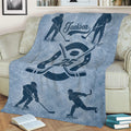 Hockey throw blanket displayed on a sofa with skating player illustrations and a bold crossed-stick emblem