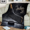 Hockey blanket draped over a couch featuring bold stick, puck, and ice rink artwork