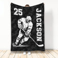 Black camouflage hockey throw blanket featuring a monochrome ice hockey player skating with a stick