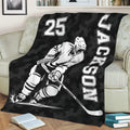 Black hockey blanket displayed on a couch with an action-style ice hockey player illustration