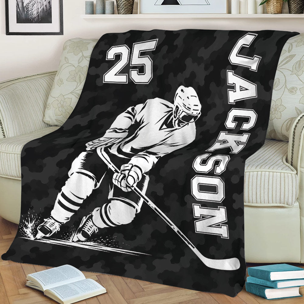 Black hockey blanket displayed on a couch with an action-style ice hockey player illustration
