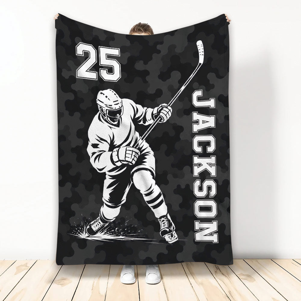 Black camouflage hockey throw blanket featuring a helmeted hockey player in action