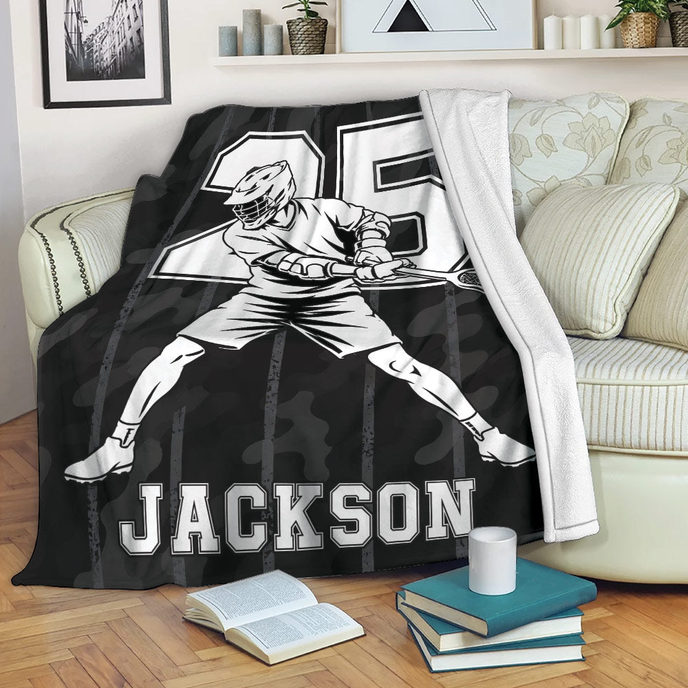 Lacrosse player throw blanket displayed on a sofa with black camouflage sports artwork and bold graphic styling