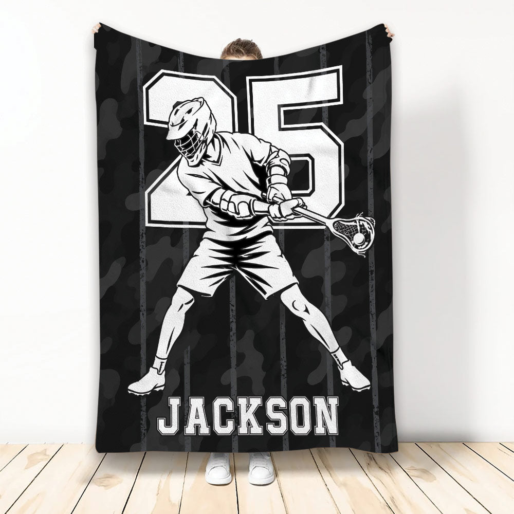 Lacrosse throw blanket with a helmeted player, lacrosse stick, bold athletic artwork, and black camouflage background