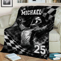 Black and white racing blanket draped over a couch with a helmeted driver and checkered flag artwork