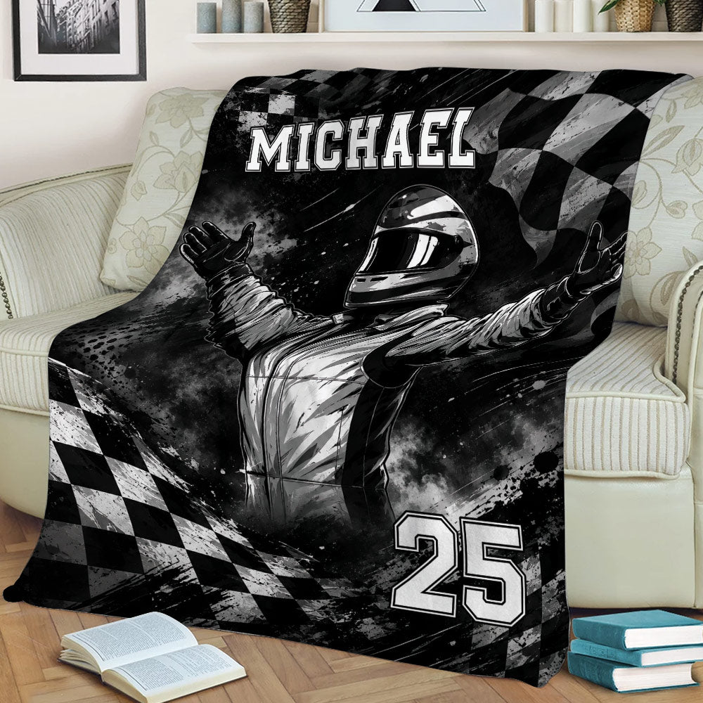 Black and white racing blanket draped over a couch with a helmeted driver and checkered flag artwork