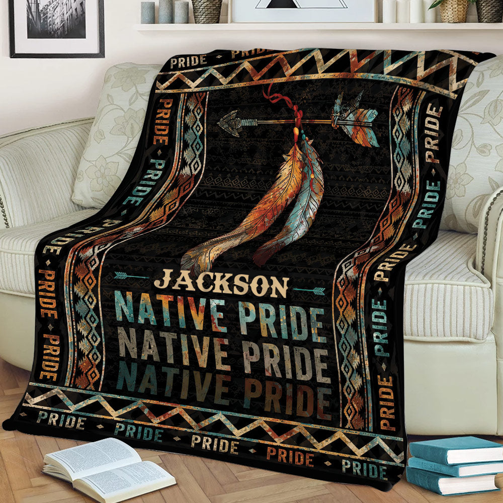 Native American-inspired throw blanket draped over a sofa with colorful feather artwork and repeating Pride details