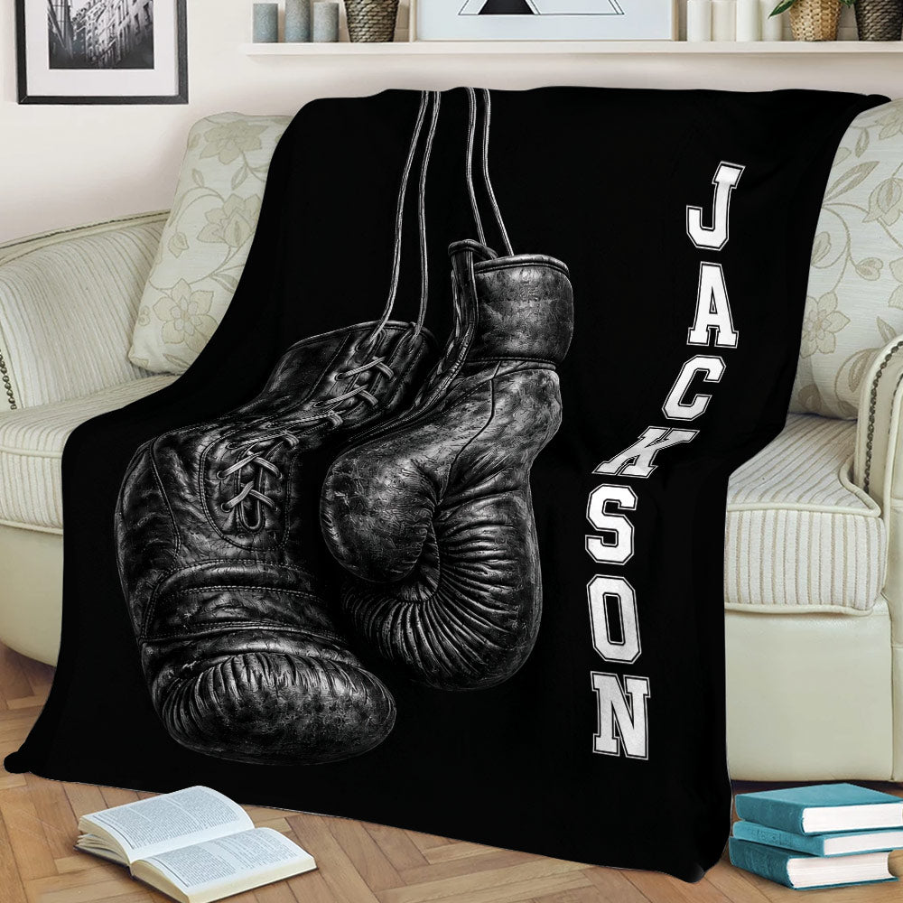 Black boxing blanket displayed on a couch with oversized realistic boxing gloves and monochrome styling