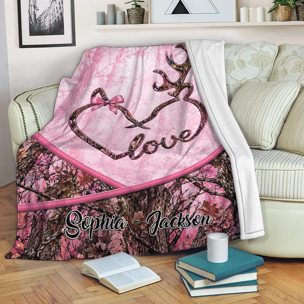 Custom deer blanket draped over a sofa with pink camouflage forest artwork and antler heart design