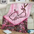 Pink camouflage deer throw blanket displayed on a couch with antler heart artwork
