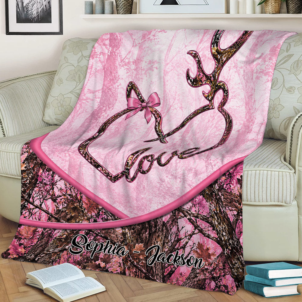 Pink camouflage deer throw blanket displayed on a couch with antler heart artwork