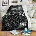 Racing throw blanket displayed on a sofa with checkered flags and dark tire-track artwork