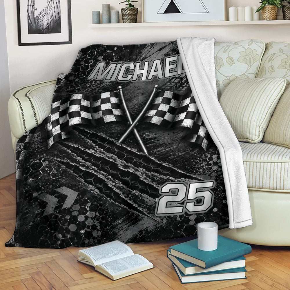 Racing throw blanket displayed on a sofa with checkered flags and dark tire-track artwork