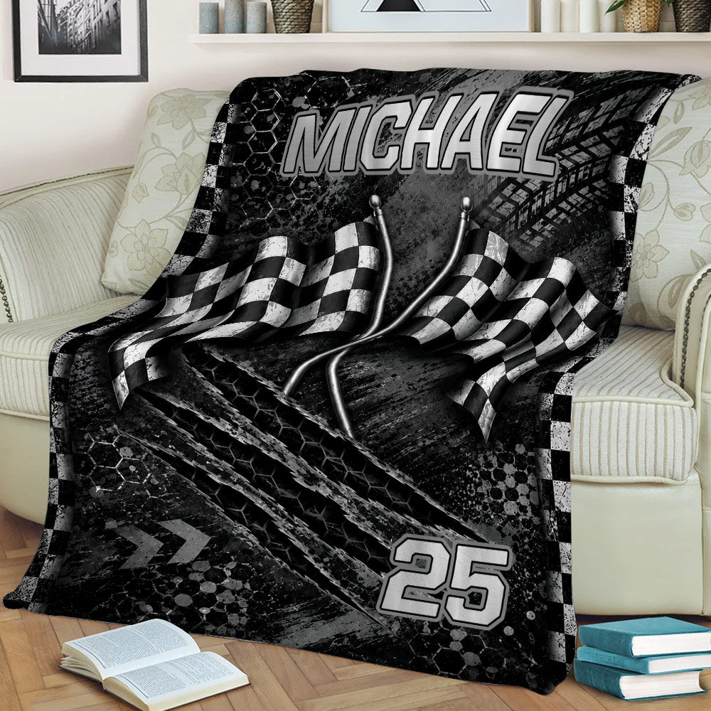 Black racing throw blanket draped over a couch with checkered flag and motorsport artwork