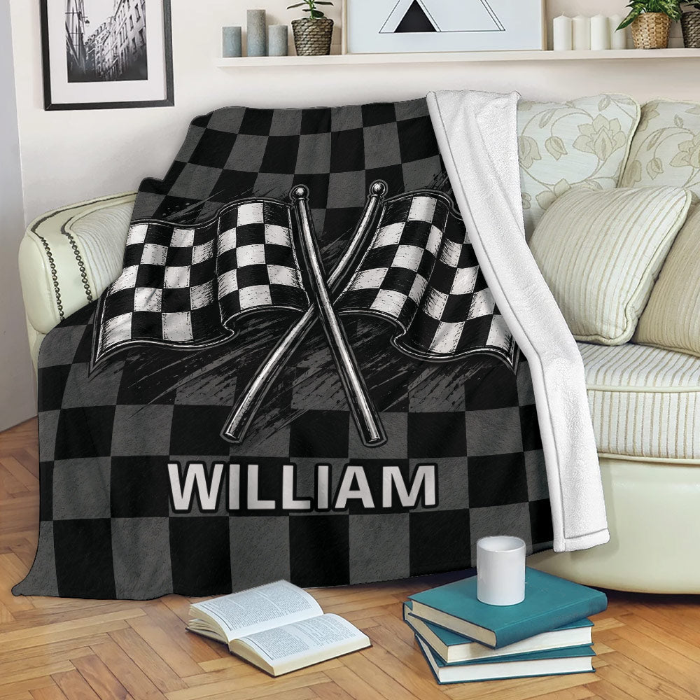 Black and gray racing throw blanket displayed on a sofa with crossed checkered flags