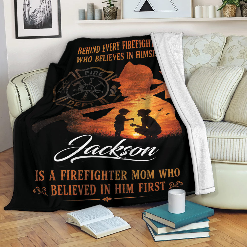 Firefighter throw blanket displayed on a sofa with a mother and child silhouette, bold orange and black artwork