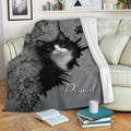 Tuxedo cat throw blanket displayed on a sofa with dramatic cracked-wall artwork